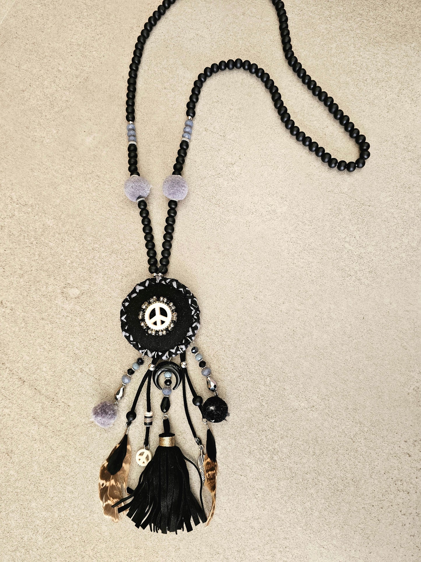 Boho black necklace with peace symbol, beads, pom-poms, and tassels