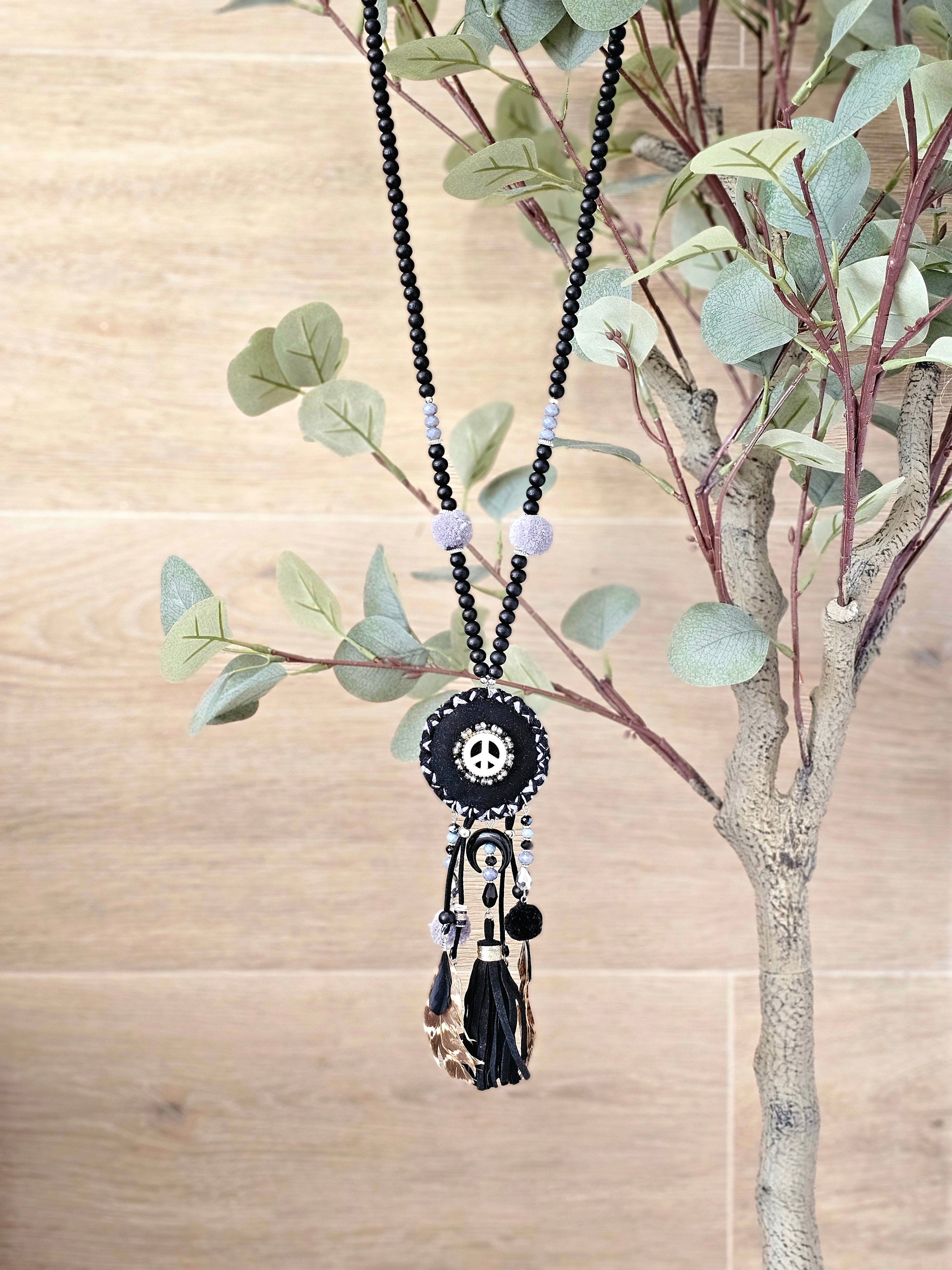 Boho black necklace with peace symbol, beads, pom-poms, and tassels